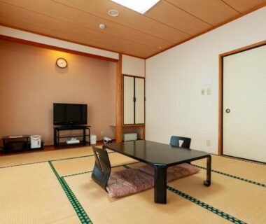 Tatami room with low table, floor cushions, TV and sliding doors at Shikino Mori in Kumamoto
