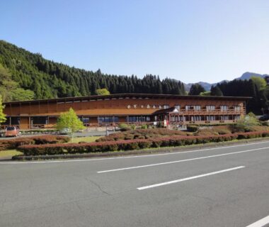 Wooden ryokan building by roadside with forested hills, Shikino Mori, Kumamoto Kyūshū