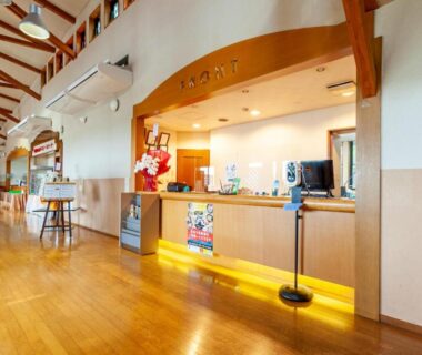 Reception area with wooden counter, beamed ceiling and polished floor at Shikino Mori in Kumamoto