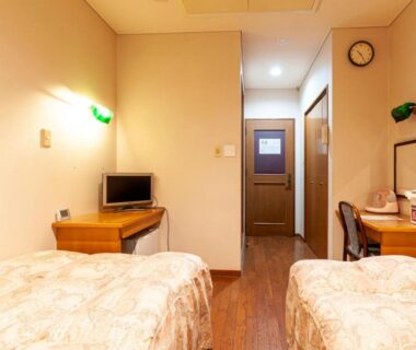 Twin beds with desk, wooden floor and small TV at Shikino Mori, Kumamoto, Kyushu
