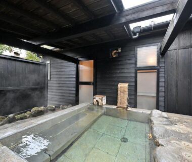 Covered onsen bath with stone edging, wooden walls and skylight at Shikinosato Hanamura, Kyushu, Japan