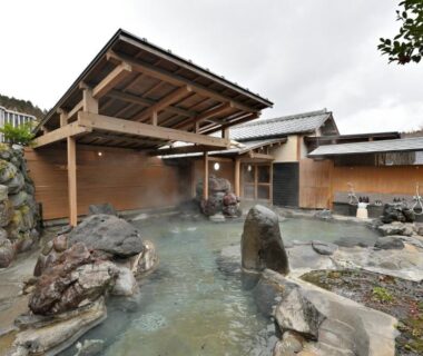 Outdoor rock onsen bath with wooden shelter at Shikinosato Hanamura, Kumamoto, Kyūshū, Japan