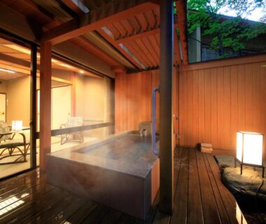 Steaming wooden onsen bath on a deck beside a tatami room with shoji screens at Shikitei Morioka TsunagiOnsen Iwate
