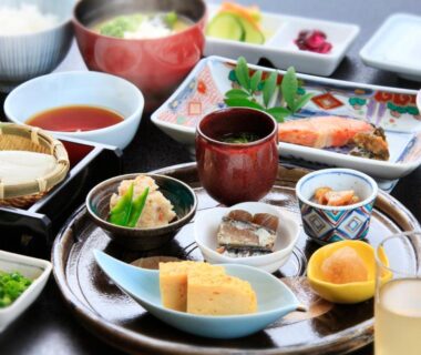 Assorted small Japanese dishes on lacquer trays with grilled fish, tamagoyaki, miso soup and pickles at ryokan breakfast