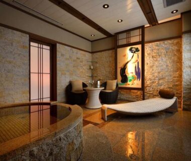 Warm stone indoor onsen with loungers, shoji screens, and decorative wall art at Shima Onsen Yoshimoto, Gunma, Kanto