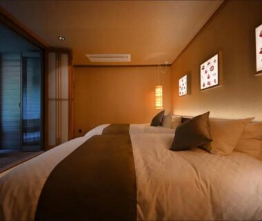 Twin beds in Japanese-style room with tatami flooring, shoji screens and soft ambient lighting at Shima Onsen Yoshimoto, Gunma