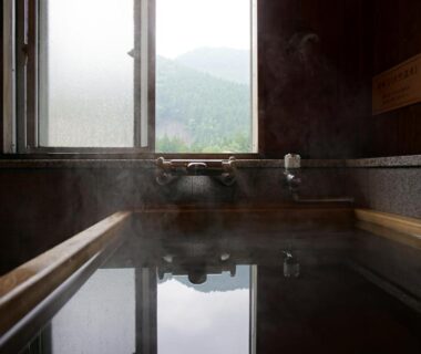Indoor wooden onsen bath with steam and misty mountain view at Shima Tamura, Gunma
