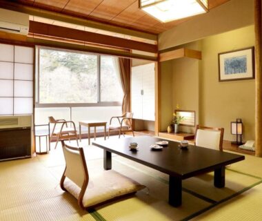 Traditional tatami room with low table, shoji screens and seating by window at Shima Tamura in Gunma