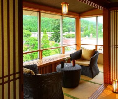 Tatami seating area with woven chairs, low table and shoji screens overlooking green Gunma hills at Shima Tamura