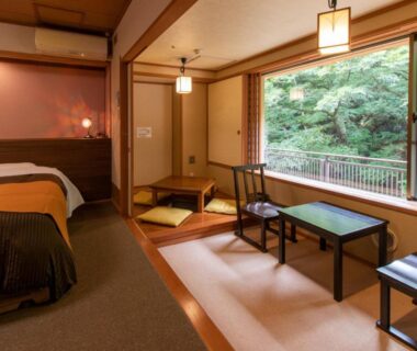 Tatami area with low table and bed at Shima Yamaguchikan, framed by verdant garden views in Gunma, Kantō