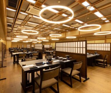 Spacious wooden dining room with partitioned booths and circular ceiling lights at Shima Yamaguchikan, Gunma