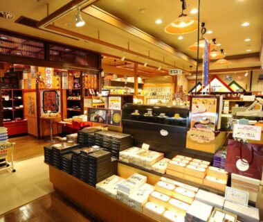 Ryokan gift shop interior at Shima Yamaguchikan in Gunma with wooden shelving and packaged souvenirs