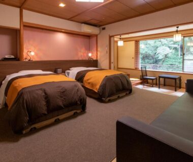 Two beds with low table by large window overlooking garden at Shima Yamaguchikan, Gunma, Kantō