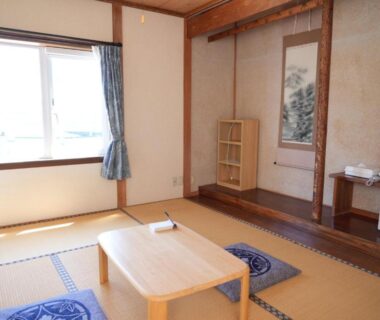 Bright tatami room with low wooden table, floor cushions, tokonoma alcove and window at Shimanoyado Kamuirishiri, Hokkaidō