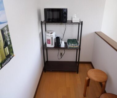 Metal shelving with TV, microwave and kettle in compact corner at Shimanoyado Kamuirishiri, Hokkaidō