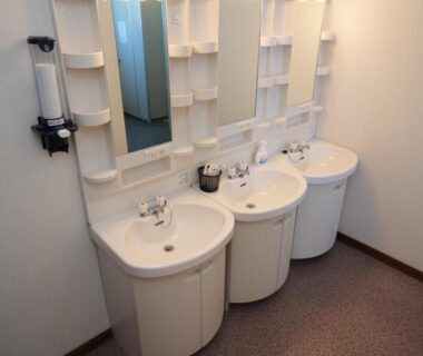 Three white washbasins with mirrors and toiletries in a guest washroom at Shimanoyado Kamuirishiri Hokkaidō