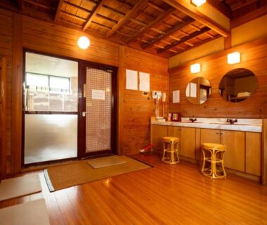 Traditional wooden changing room with sinks, round mirrors, stools and towel shelves at Shimaya in Nagano