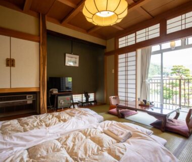 Tatami room with futon bedding, shoji screens and balcony overlooking greenery at Shimaya in Nagano