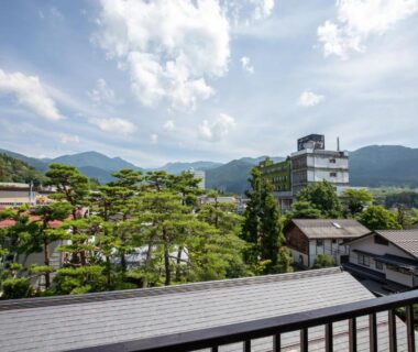 Balcony railing overlooking rooftops, pine trees and distant mountains at Shimaya in Nagano, Japan