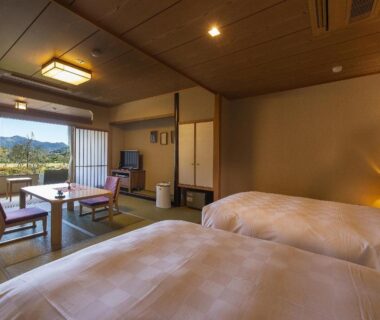 Twin beds, tatami seating and shoji screens with distant mountain view at Shimoda Central Hotel, Shizuoka