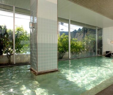 Tiled indoor bathing pool with floor-to-ceiling windows and green foliage outside, Shimoda Kaihin Hotel Shizuoka