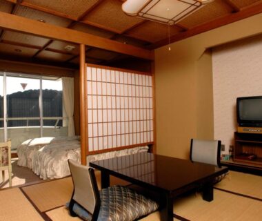 Tatami room with low table, futon, shoji screens and TV, sliding balcony door at Shimoda Kaihin Hotel, Shizuoka