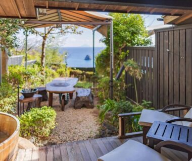 Wooden soaking tub and terrace seating with distant sea view at Shimoda View Hotel Shizuoka
