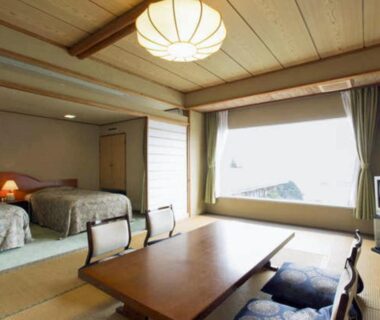 Tatami room with low table, zabuton cushions and two beds at Shimoda View Hotel in Shizuoka