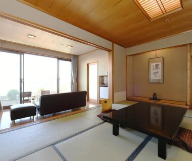 Tatami room with low table and sofa by sliding glass doors at Shimoda Yamatokan, Shizuoka, Chūbu Japan