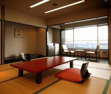 Tatami room with low red table, zaisu chairs and window seating at Shinki, Gunma