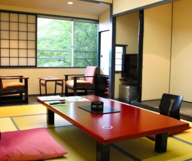 Traditional tatami room with low red table, zabuton cushions, shoji screens and garden view at Shinki in Gunma, Kantō