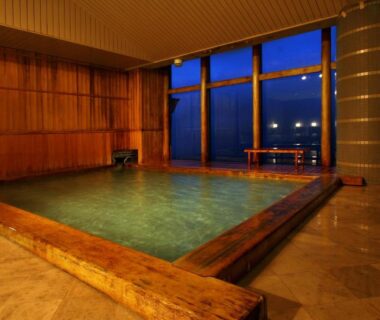 Spacious indoor onsen bath with wooden surround and floor-to-ceiling windows at Shinki, Gunma Kantō