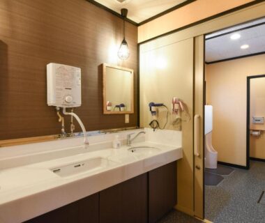 Shared washroom with three sinks, mirrors and restroom doorway at Shinseikan in Iwate