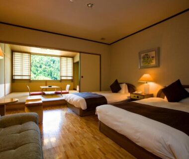 Ryokan room with tatami seating, twin beds, shoji screens and leafy window view at Shinshiyo, Ōita
