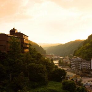 Shinshiyo buildings on a forested hillside overlooking a river valley at golden hour in Ōita, Kyūshū