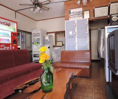 Lounge with sofa, wooden table and vase, vending machines and lockers at Shintaku Sanso Nagano