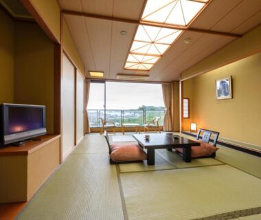 Traditional tatami room with low table, zabuton cushions, shoji screens and wide window overlooking landscape