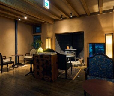 Dimly lit wooden lounge with low tables, chairs and soft lanterns at Shinwaen in Kumamoto, Kyūshū