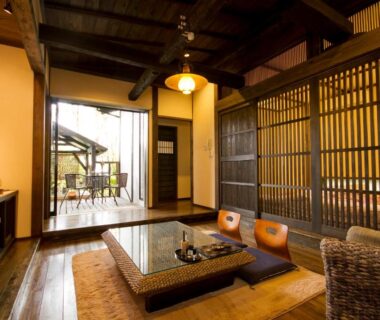 Traditional Japanese sitting area with low table, floor cushions, wooden lattice partition and garden view at Shinwaen in Kumamoto