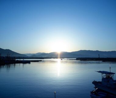 Sunrise over calm harbor with moored boats and distant mountains near Shinwaka Lodge, Wakayama