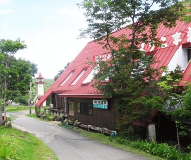 Red sloped roof building with driveway and trees at Shinyu Onsen Kurikomaso in Miyagi Tōhoku
