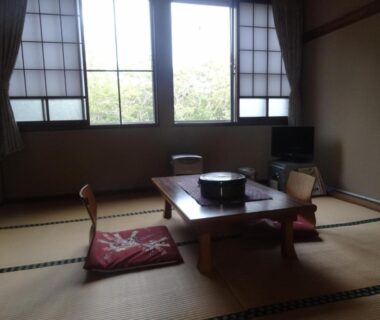 Tatami room with low table and floor cushions, shoji screens and window view at Shinyu Onsen Kurikomaso, Miyagi