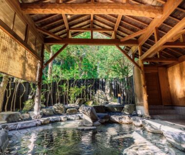 Rock-lined covered onsen bath with wooden beams at Shinzan Kinosaki Hyōgo Kansai
