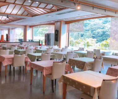 Spacious dining hall with set tables and floor-to-ceiling windows overlooking garden at Shiobara Onsen Hotel Ohruri Tochigi