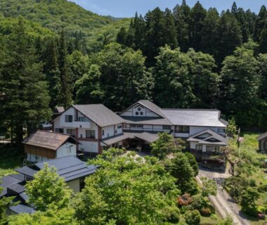 Traditional ryokan buildings surrounded by dense forest and mountain slopes in Yamagata, Tōhoku, Japan
