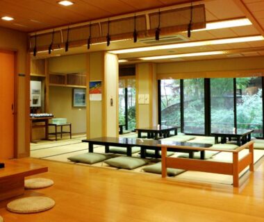Spacious tatami room with low tables and floor cushions overlooking garden at Shirafune Grand Hotel Nagano