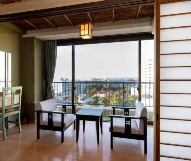Japanese room with shoji screens, low chairs and balcony overlooking town in Wakayama