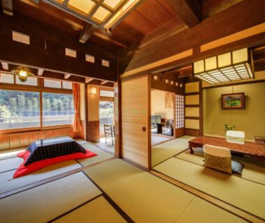 Spacious tatami room with low tables, zabuton cushions and large window overlooking greenery