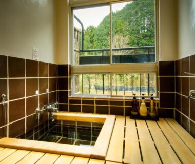 Wooden soaking tub beside tiled walls and window, Shirakabe ryokan, Shizuoka