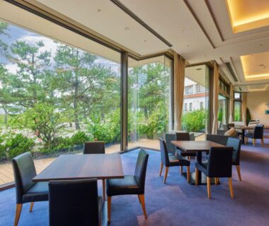 Spacious lounge with tables and floor-to-ceiling windows overlooking greenery at Shiraraso Grand Hotel in Wakayama, Kansai, Japan